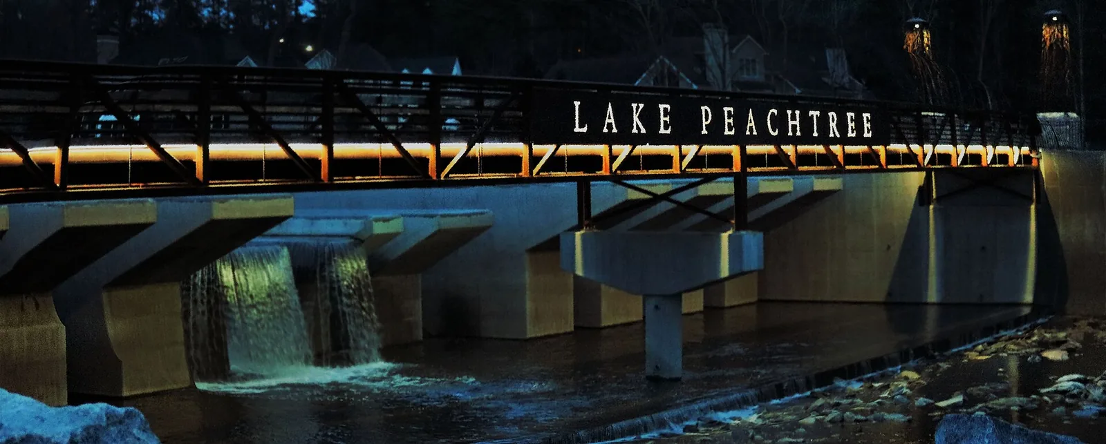 The Lake Peachtree bridge, with its name in lights, at night in Peachtree City