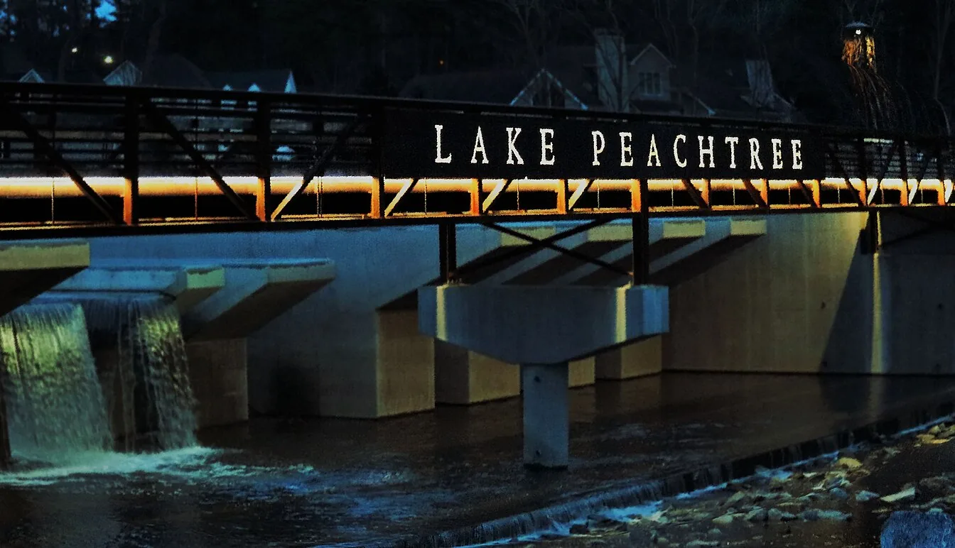 The Lake Peachtree bridge lit up at night in Peachtree City