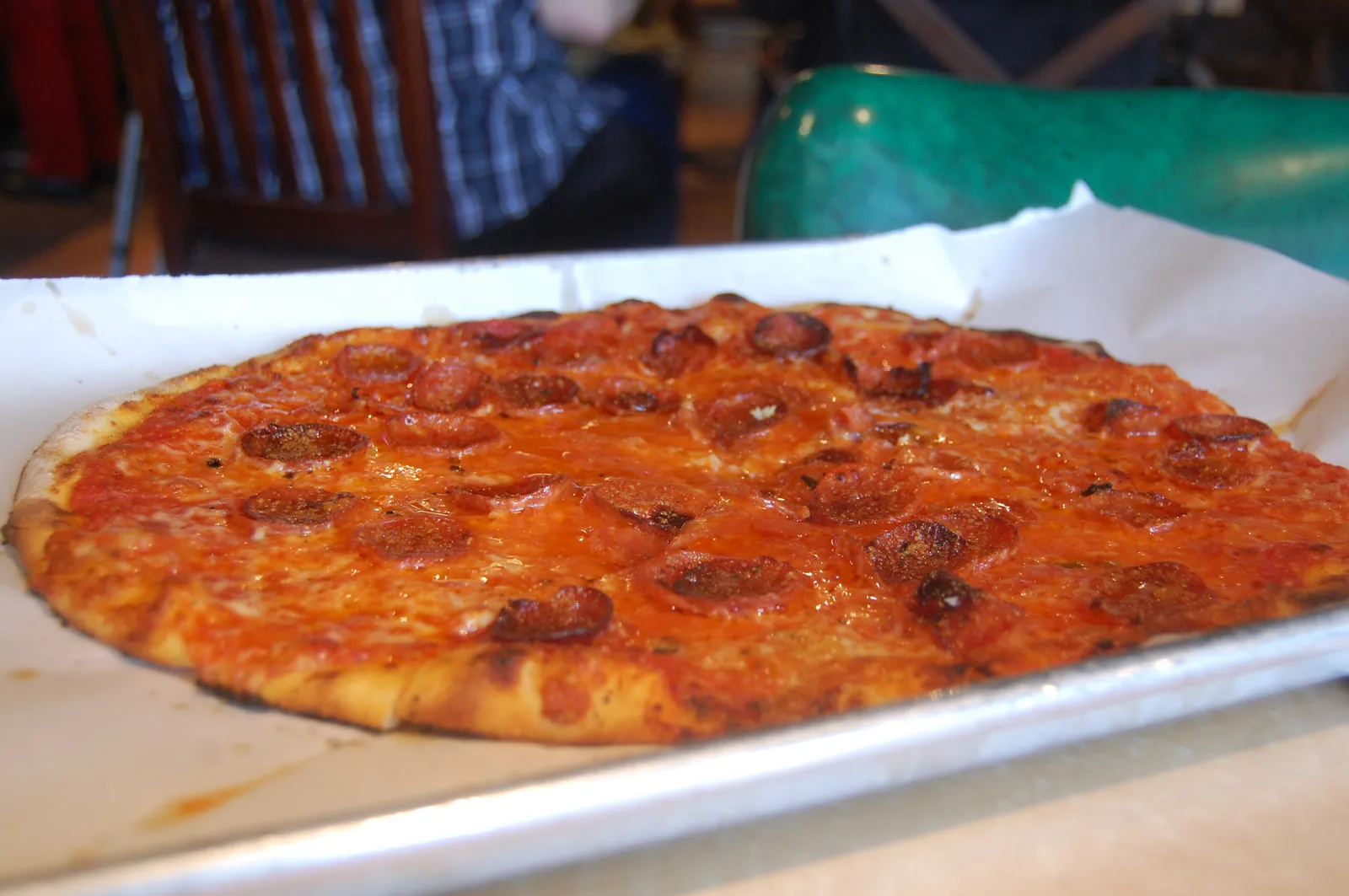 A thin-crust pepperoni pizza on a metal tray. The photo was not taken at a Peachtree City restaurant.